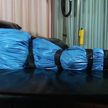 Unterwürfiges Mädchen wird in einen blauen Latex gewickelt