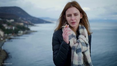 Russian babe with scarf smoking a cigarette by the river — 9