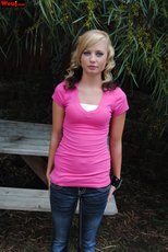 Cute looking girl posing in a pink shirt and jeans outdoors — 15