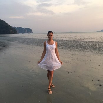 Doce bebê Lovenia Lux posando com um vestido branco na praia