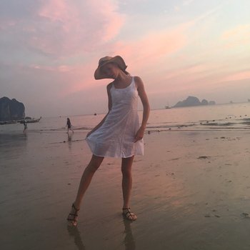 Doce bebê Lovenia Lux posando com um vestido branco na praia