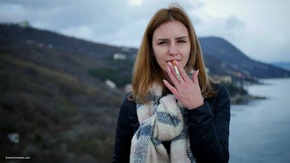 Russian babe with scarf smoking a cigarette by the river — 1