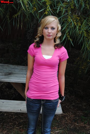 Cute looking girl posing in a pink shirt and jeans outdoors - 000013