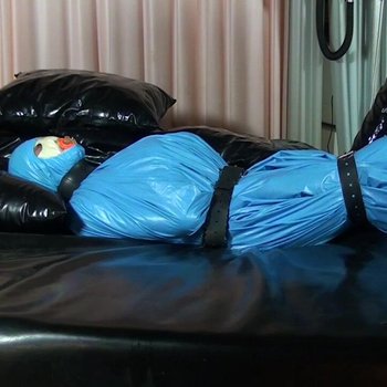 Unterwürfiges Mädchen wird in einen blauen Latex gewickelt