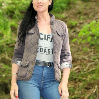 Chica morena bonita posando con una camisa y jeans al aire libre